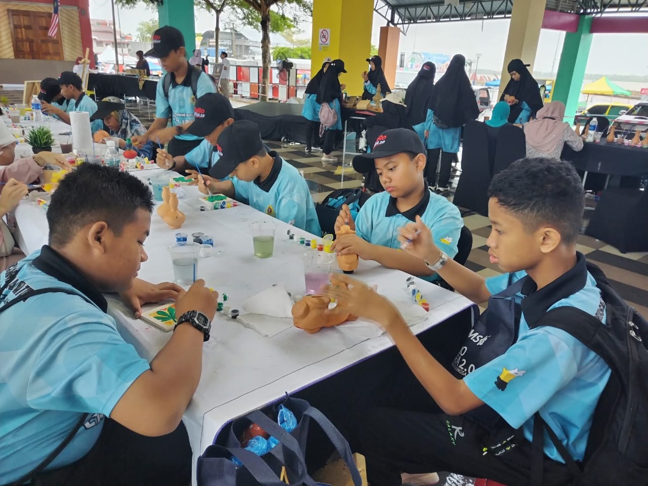 Participants painting small clay pieces with brushes at a long table